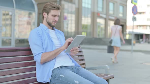 Man Using Tablet While Sitting Outdoor on Bench