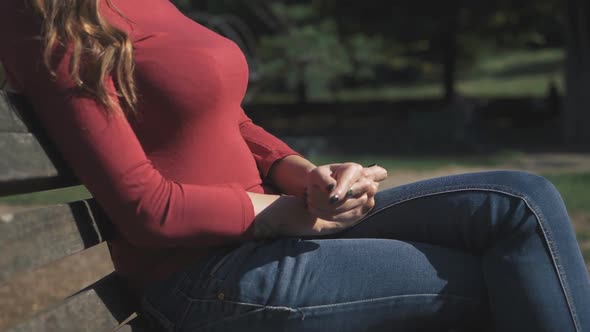 Nervous  sexy woman 's hands sitting on te bench in the park-slow motion