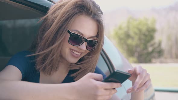 Beautiful Lady Scrolls Social Media on Cellphone in Car