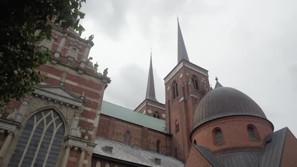 Slow motion shot of Roskilde Cathedral with grey skies in the background as seen from the ground und