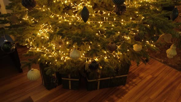 Close up of a Christmas tree decorated with balls and a gifts under it.