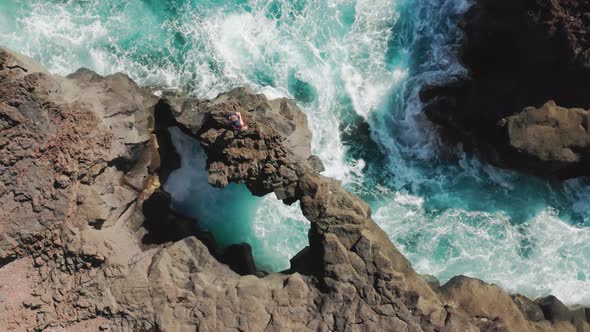 Man Stands on the Edge of the Rock As Seen From the Top