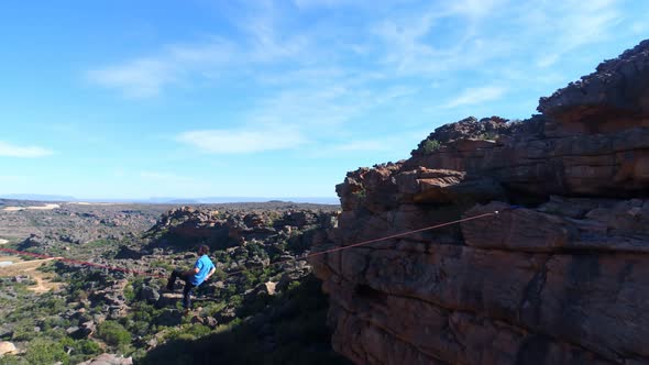 Male highliner sitting on rope and balancing in countryside 4k