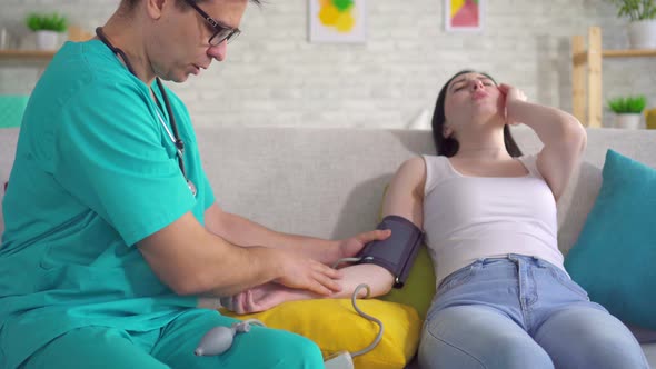 Male Doctor Measures a Young Woman's Blood Pressure with a Tonometer Close Up