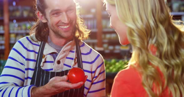 Male staff assisting woman in selecting fresh vegetables