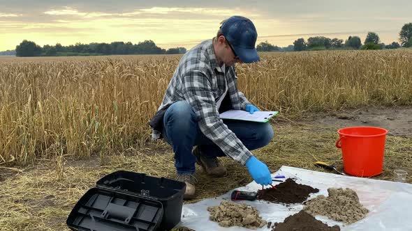 Agronomist Tuning Digital Device for Soil Measurements at Field Dawn