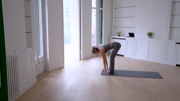 Flexible woman doing yoga on mat at home
