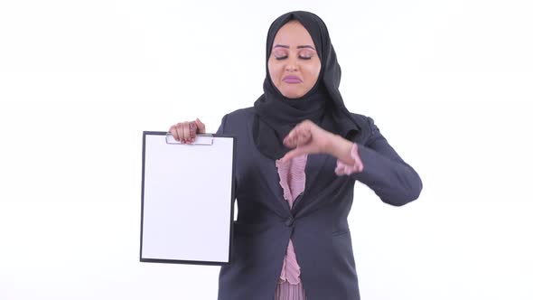 Stressed Young African Muslim Businesswoman Showing Clipboard and Giving Thumbs Down
