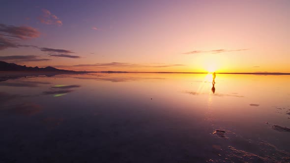 Person walking past the sun reflecting in the Great Salt Lake at sunrise