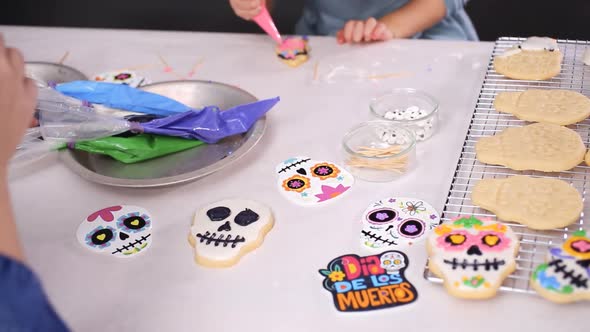 Step by step. Mother and daughter decorating sugar skull cookies with royal icing for Dia de los Mue