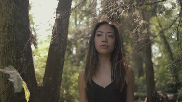 Closeup of asian woman in black looking forward and exploring sunny forest, Slowmo