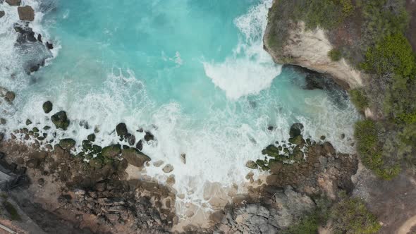 Overhead view of waves breaking inside a small rocky bay