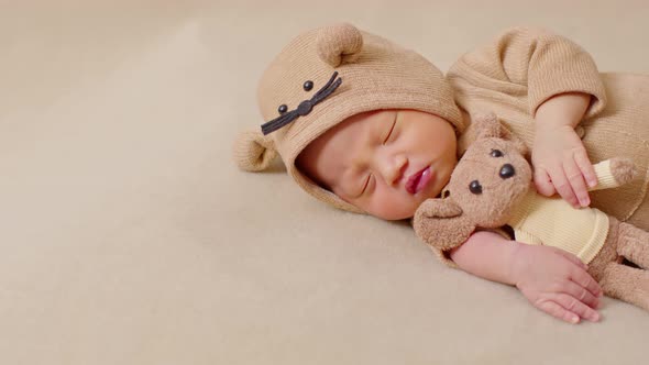 happy newborn baby weaing cute Mouse costume lying sleeps and hug doll on Beige background