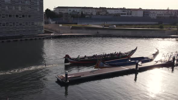 People sailing with massive canoe in canal of Aveiro city, aerial view