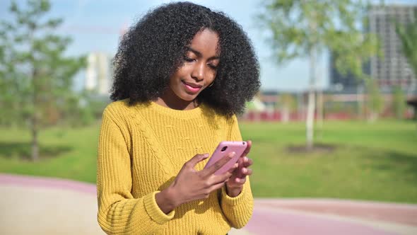 young black woman makes a selfie on the phone on a bright sunny day