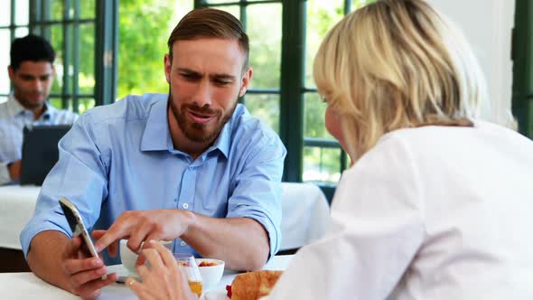 Male and female executives discussing over mobile phone 4k