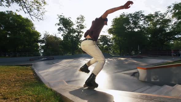 Aggressive Inline Roller Skater Doing Tricks in Concrete Skatepark Outdoors Slow Motion