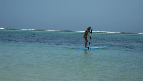 A Teenage Girl On Stand Up Paddle Board on crystal clear indian ocean in summer