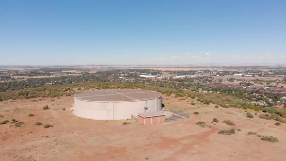 DRONE Shot of Water Supply Tank supplying water to a Town in the Background on a Sunny Day