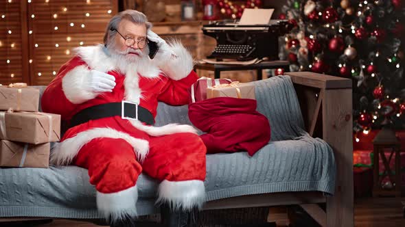 Confident Male Santa Claus Talking Use Smartphone at Festive Garland