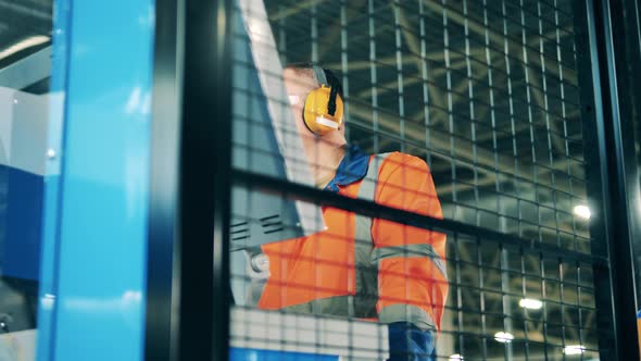 Engineer is Being Shot Through a Grid While Operating a Factory Machine