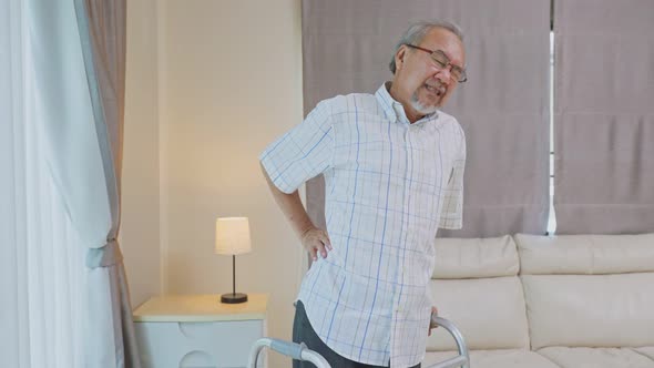 Asian Senior elderly disabled man patient walking slowly with walker or cane at nursing home care.