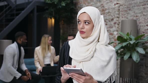 Muslim Businesswoman in Hijab Typing on i-pad and Standing in the Modern Office