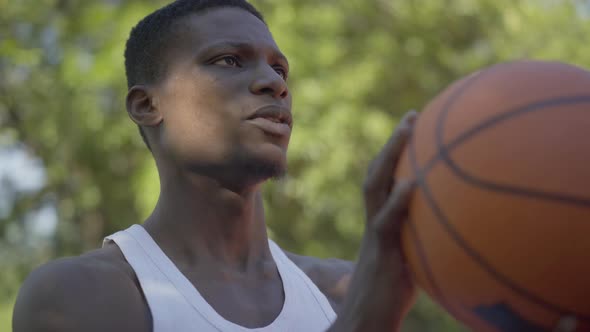 Close-up of Concentrated African American Sportsman Throwing Ball Into Basketball Hoop. Portrait of