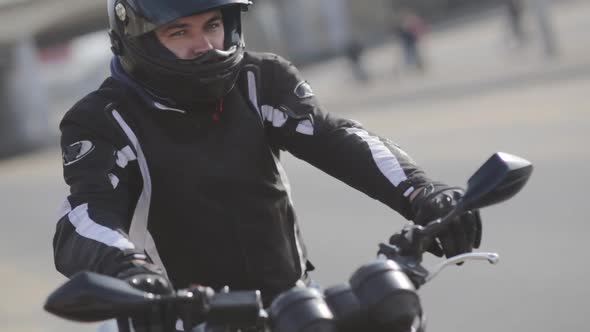 Young Attractive Man Motorcyclist with Black Helmet and Sport Motorcycle on Street