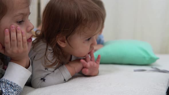 Smiling Preschool Toddler Children In Pajamas Watching Cartoon on Smartphone on Bed