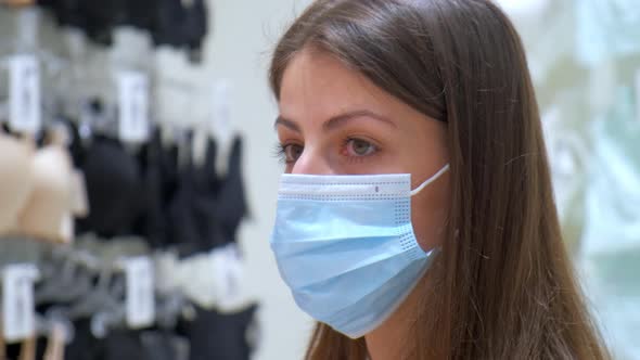 Young Woman with Mask Walks in Underwear Department in Mall