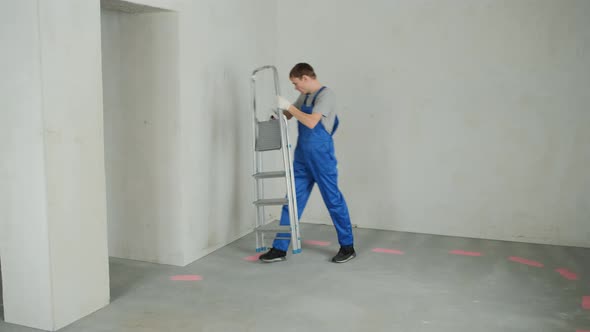 Repairman with Ladder Inspects House to Renovate