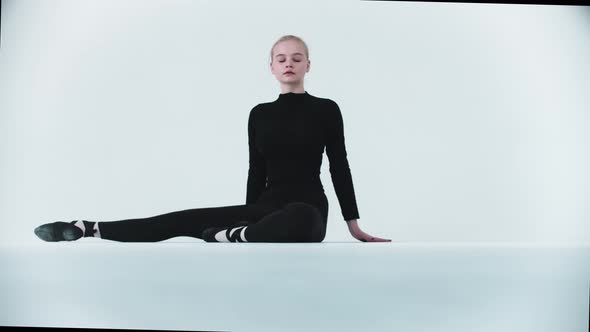 Gymnastics  Young Woman Sitting in a Split and Looking in the Camera