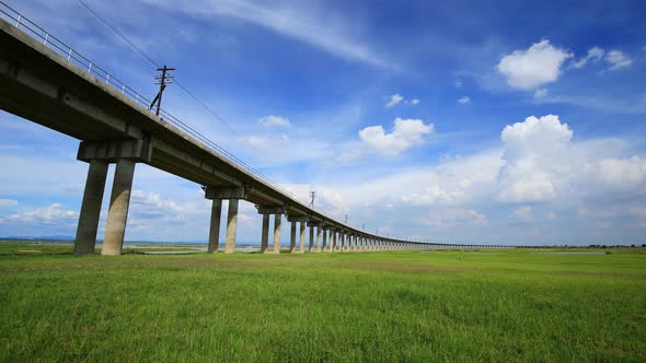 Time-lapse of Bridge of railway cross grass field meadow at Pasuk River Dam in summer, Lopburi