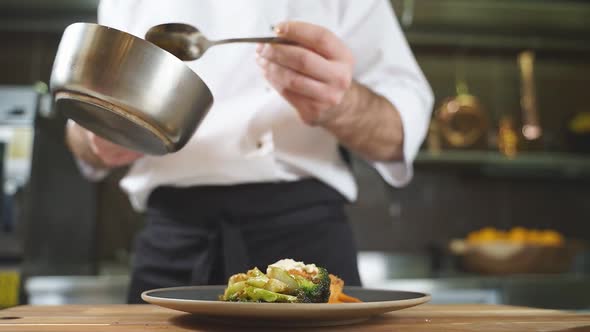 The Chef of the Restaurant Pours Sauce on a Delicious Dish