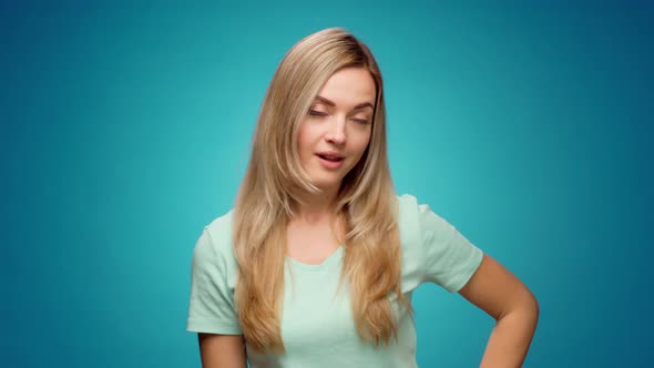 Young Woman Pointing Fingers Down Showing Copy Space Against Blue Background