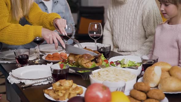 Female Hands Which Using Fork and Knife to Cut Roast Turkey During Family Dinner