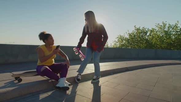 Lovely Multiracial Females with Skateboards Meeting for Ride in Morning