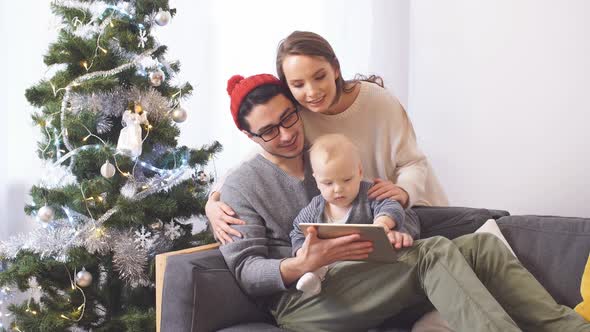 Happy Family Hugging on the Background of Christmas Tree