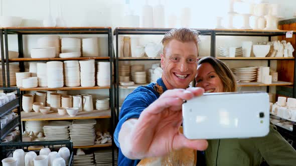 Male and female potter taking selfie with mobile phone