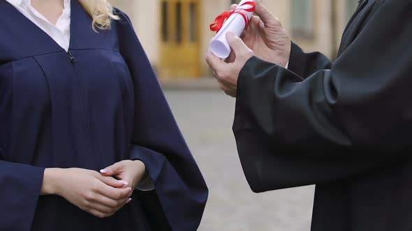 Dean of faculty expressing gratitude and handing diploma to female student