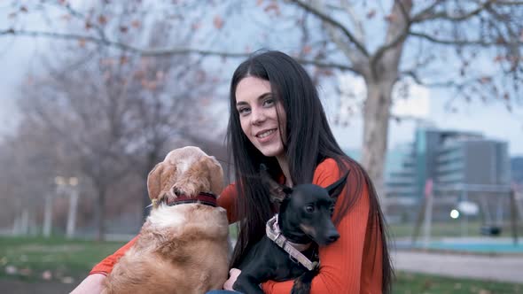 Woman hugging and stroking her dogs while enjoying together outdoors in the park. Pets concept.