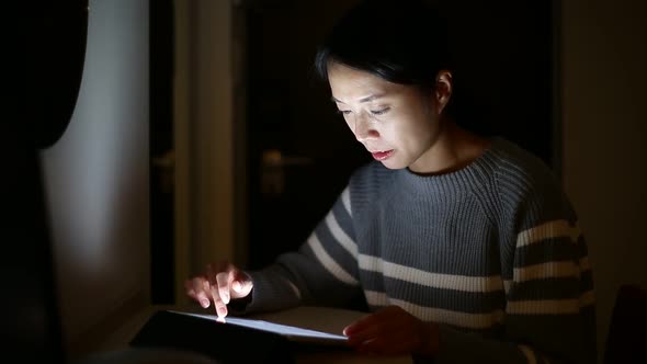 Woman using tablet computer at home in the night time