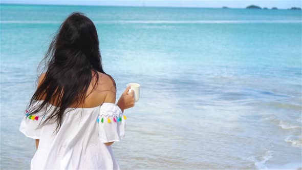 Young Woman with Cup of Tea Relaxing on the Beach