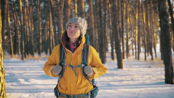 A Young Caucasian Girl with Backpack Going on Winter Forest Road in Snow Covered Winter Pine Forest