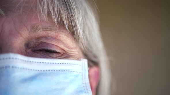 Close up of an old woman face and eye with a medical patient mask to prevent spreading a contagious