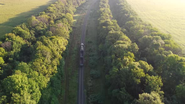 Freight Train with Two Empty Cars a Tractor on the Railway Tracks Goes Out of Town