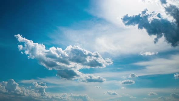 White Fluffy Clouds Slowly Float Through the Blue Daytime Sky Timelapse