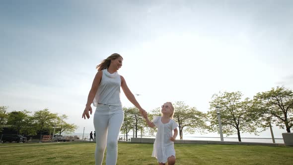Mother and Daughter in the Park on a Running Together on Sunny Day
