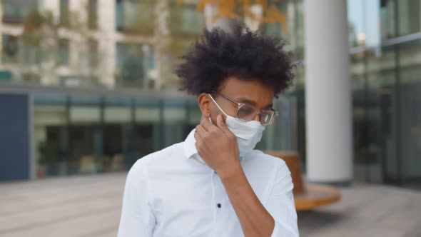 Portrait of Young African Businessman Walking Outdoors Business Center Putting Off Safety Mask